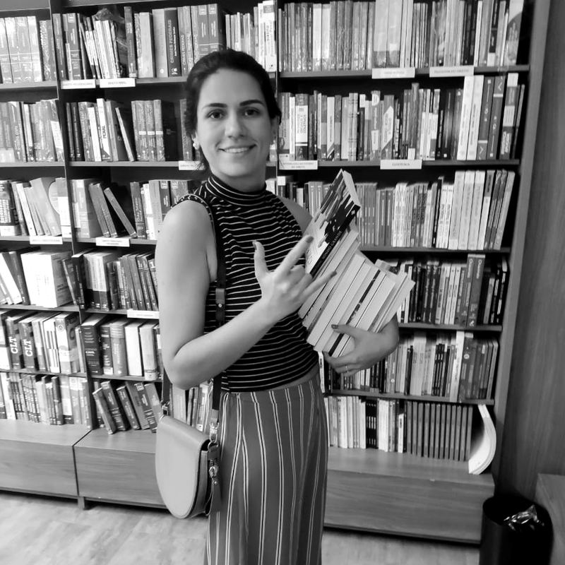 Anna numa livraria com uma pilha de livros