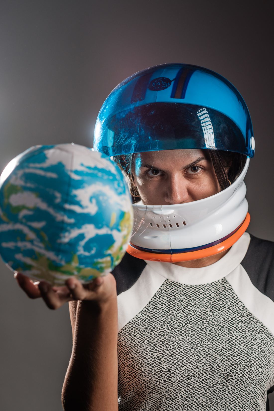 Anna com capacete de astronauta, segurando um globo à frente
